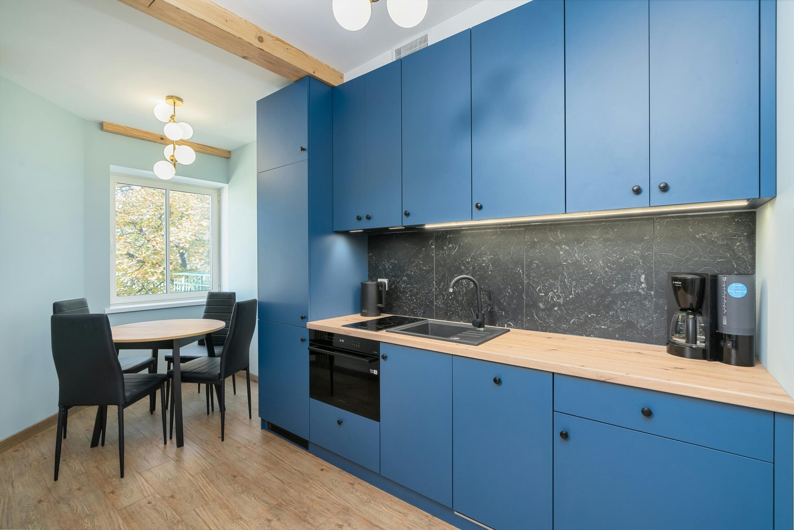Stylish kitchen featuring blue cabinets and a minimalist dining area with natural light.