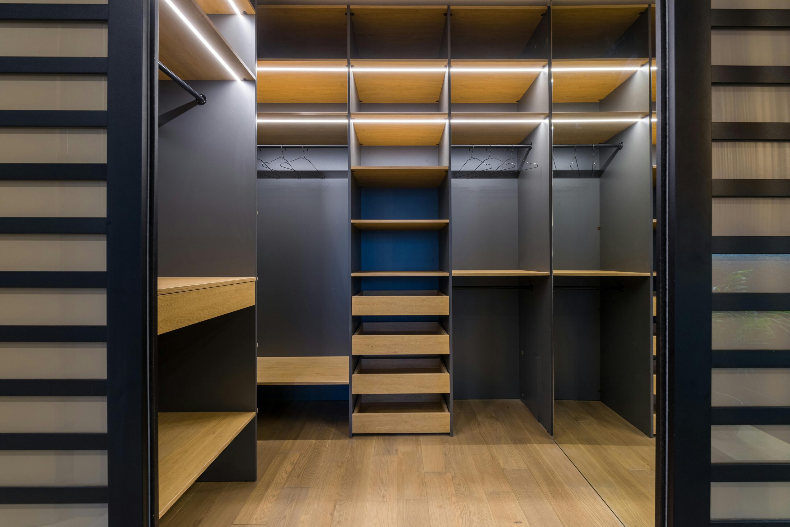 Spacious and contemporary walk-in closet featuring wooden shelves and ambient lighting.